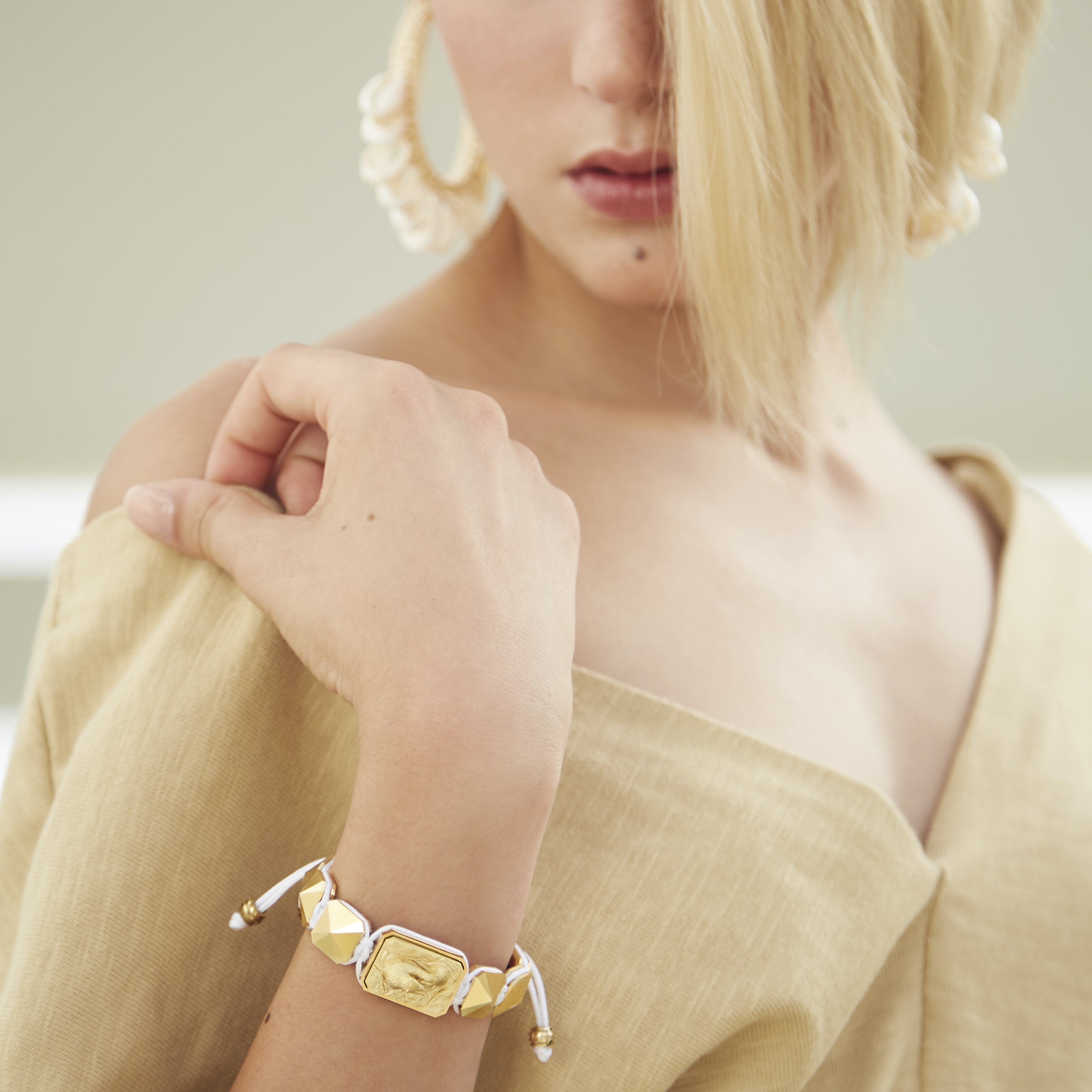 Proud Of You bracelet with ceramic and sculpture finished in 18k Yellow Gold complemented with a white coloured cord.